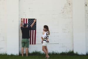 young couple and child hanging an American flag