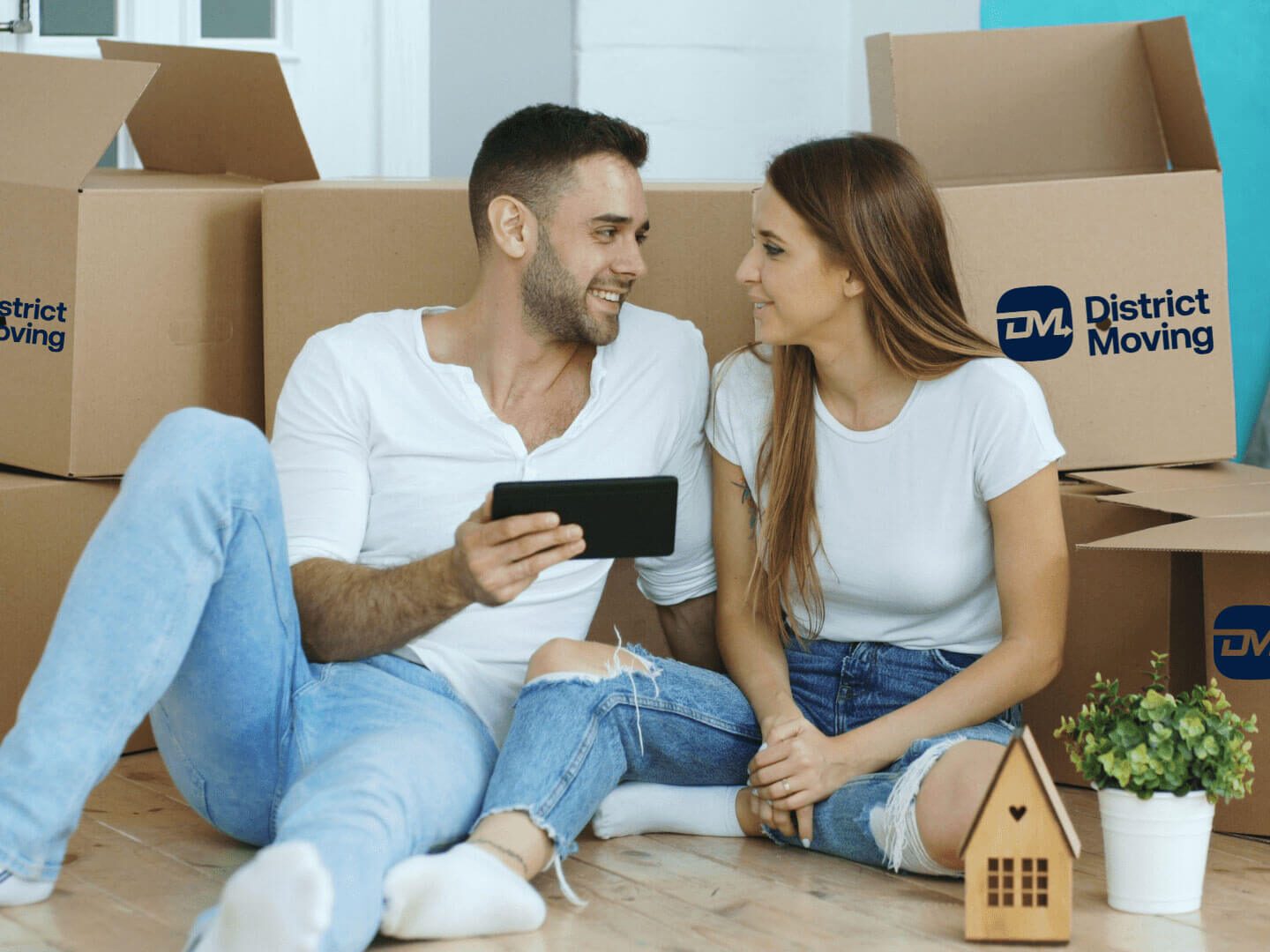 Young couple sitting on floor using tablet computer after moving